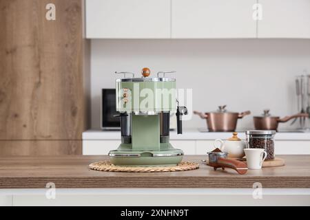 Moderne grüne Kaffeemaschine mit einem Becher Bohnen auf dem Tisch in der Küche Stockfoto