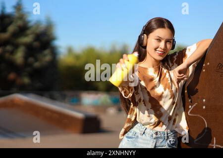 Junge asiatische Frau in Kopfhörern mit Sprühdose im Skatepark Stockfoto