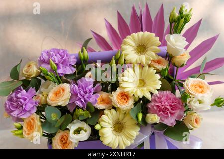 Der Blumenstrauß liegt anmutig in einer luxuriösen lila Box mit einer Mischung aus Farben und Texturen. Stockfoto