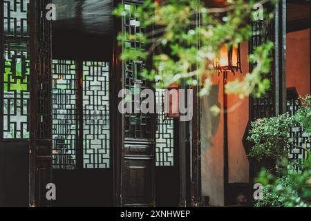 Ein Blick durch ein traditionelles chinesisches Fenster mit komplizierten Gittern, der einen Blick auf einen friedlichen Garten freigibt. Stockfoto