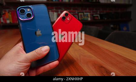 14. Juli 2023 Eskisehir Türkei. Mann, der das blaue iphone 13 und das rote iphone 11 in der Hand hält Stockfoto