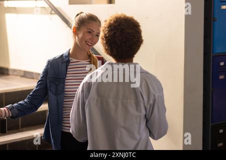 In der Highschool sprachen und lächelten Teenager im Flur in der Nähe von Schließfächern Stockfoto