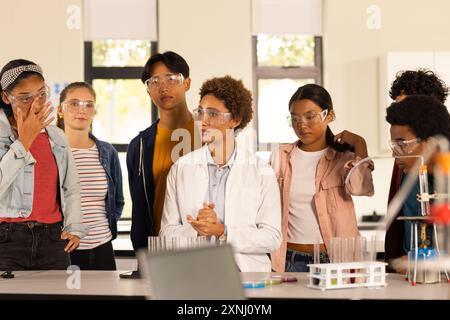 Schutzbrille tragen, Teenager hören Lehrern im Wissenschaftsunterricht an der High School zu Stockfoto