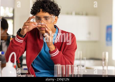 In der Highschool untersuchte ein Teenager das Reagenzglas im Wissenschaftsunterricht und trug eine Schutzbrille Stockfoto