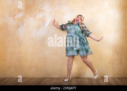 Fröhliches kurviges Model springt in ein Studio und drückt Freude und Selbstvertrauen aus Stockfoto