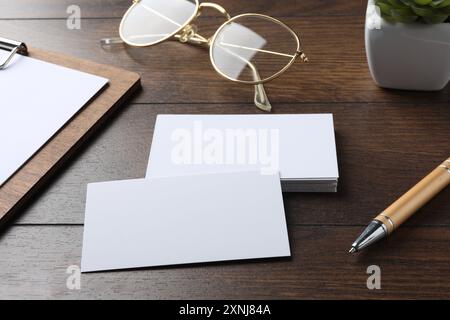 Leere Visitenkarten, Klemmbrett mit Blatt, Gläser und Stift auf Holztisch. Modell für Design Stockfoto