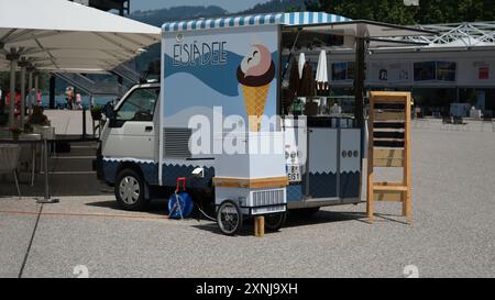 Ein kleiner Eiswagen mit blauem und weißem Design. Das Fahrzeug steht auf einer Schotterfläche Stockfoto