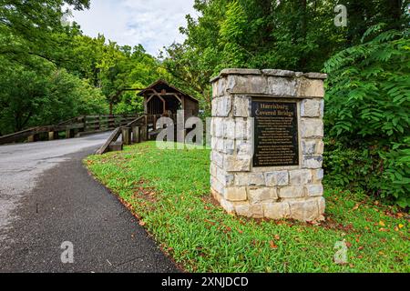 Sevierville, Tennessee, USA – 23. Juli 2024: Gedenktafel mit der 1875 erbauten Harrisburg Covered Bridge, im Hintergrund sichtbar. Stockfoto