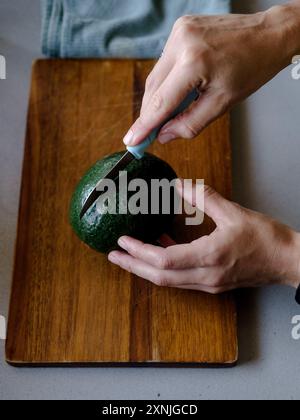 Eine Person, die eine Avocado auf einem Schneidebrett schneidet Stockfoto