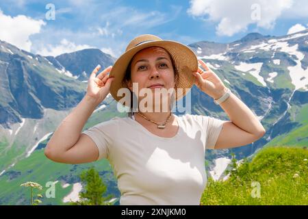 Eine Frau mit Strohhut genießt an einem sonnigen Tag den Blick auf die Bergwelt Stockfoto