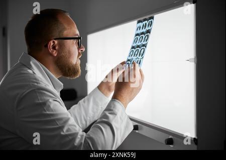 Arzt untersucht MRT-Ergebnisse. Der im Krankenhaus tätige Facharzt führt die Beschreibung der Röntgenbilder des Patienten durch. Konzept der modernen Diagnostik. Stockfoto