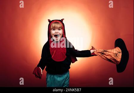 Halloween Hexe mit einem geschnitzten Kürbis und magischen Lichtern in einem dunklen Wald. Kinder spielen mit Kürbissen und verwöhnen. Halloween Kleider und Hexenkleider Stockfoto