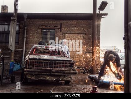 Teenager optimieren ihre Stock Cars in einer Werkstatt und bereiten sich auf ein bevorstehendes Rennen vor. Das Bild zeigt Teamarbeit, Engagement und praktisches Lernen. Stockfoto