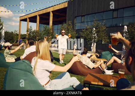 Fröhliche junge Leute, Freunde treffen sich im Café im Freien, Picknick im Freien mit erfrischendem Bier und fröhlichen Gesprächen Stockfoto