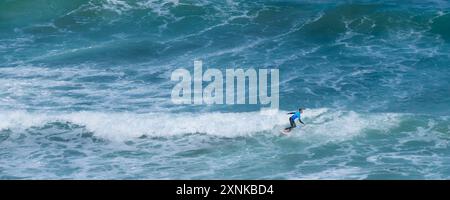 Ein Luftbild eines einsamen Surfers, der vor der Küste von Newquay in Cornwall in Großbritannien auf einer Welle reitet. Stockfoto