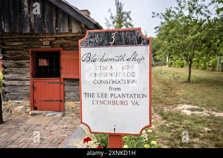 Schmiedewerkstatt Außenschild Shenandoah Heritage Village Luray Virginia | LURAY, Virginia, Vereinigte Staaten — Ein handgemaltes Schild datiert die Schmiedewerkstatt auf etwa 1850, gebaut aus Kastanienholz und von der Lee-Plantage in der Nähe von Lynchburg, Virginia, hierher gebracht. Die rot gerahmte Blockhütte ist eines von mehreren Gebäuden aus dem Shenandoah-Tal, die in das sieben Hektar große Shenandoah Heritage Village verlegt wurden, das 2010 auf dem Gelände der Luray-Höhlen eröffnet wurde. Die nummerierten Schilder führen Besucher durch ein gesammeltes Freilichtmuseum von Volksbauweise-Bauernhäusern, die vor dem Abriss in der gesamten Region gerettet wurden. Stockfoto