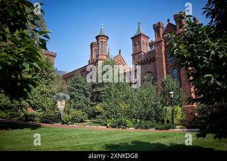 Smithsonian Castle Enid A Haupt Garden Washington DC // WASHINGTON DC — das Smithsonian Castle wird durch den Enid A. Haupt Garden auf der National Mall in Washington, D.C. besichtigt. Das rote Sandsteinschloss wurde 1855 fertiggestellt und dient als Hauptsitz und Besucherzentrum der Smithsonian Institution. Der 4 Hektar große Hauptgarten mit formellen Bepflanzungen und Springbrunnen wurde 1987 als Teil des Quadrangle-Komplexes eröffnet. Stockfoto