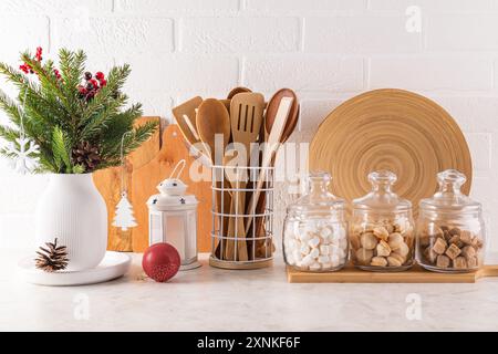 Fichtenstrauß in einer weißen Vase, Weihnachtsdekoration auf der Arbeitsplatte Küche, umweltfreundliche Utensilien. Gläser mit Bulk-Produkten für den Urlaub. Stockfoto