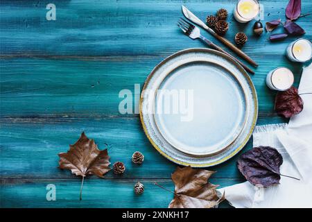 Ein einfacher Ort für den Urlaub mit Teller, Serviette, Besteck und Teekerzen auf einem blau grün dekorierten Tisch aus flacher Lage oder von oben. Stockfoto