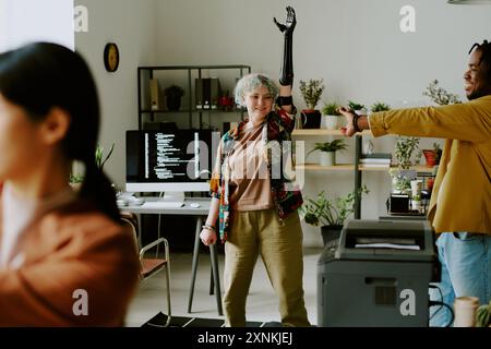 Gruppe freudiger Z-Kollegen verschiedener Generation, die einfache Dehnübungen im modernen Büro mit biophiler Innenarchitektur durchführen Stockfoto