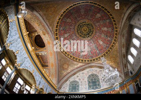 ISTANBUL, Türkei / Türkiye — die Kuppeldecke im opulenten Thronsaal des Kaiserreichs im Harem des Topkapi-Palastes, Istanbul. Diese aufwendig verzierte Kammer, die mit komplizierten Iznik-Fliesen, vergoldeten Ornamenten und reichen Möbeln geschmückt war, diente als privater Audienzsaal für den osmanischen Sultan innerhalb der abgeschiedenen Grenzen des kaiserlichen Harems. Der Raum spiegelt die künstlerische Meisterschaft und den Luxus der osmanischen kaiserlichen Architektur wider und bietet einen Einblick in die Welt des osmanischen Hofes. Stockfoto