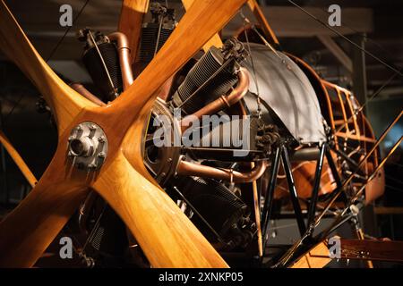 WWI Biplane Wooden Propeller Rotary Engine Close Up Air and Space Museum | WASHINGTON D.C., Vereinigte Staaten — Ein geschnitzter hölzerner Propeller mit vier Flügeln umrahmt die freiliegenden Zylinder und Kupferrohre eines frühen rotierenden oder radialen Flugzeugtriebwerks im Smithsonian National Air and Space Museum. Drehmotoren aus der Zeit des Ersten Weltkriegs drehten den gesamten Zylinderblock mit dem Propeller und erzeugten so ein Drehmoment, dass Piloten normalerweise Kurven in eine Richtung gegenüber der anderen bevorzugten. Stockfoto