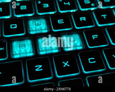 Eine Nahaufnahme einer blauen hintergrundbeleuchteten RGB-Tastatur auf einem Gaming-Notebook in der dunklen Umgebung. Bild mit selektivem Fokus Stockfoto