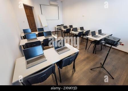Inneneinrichtung eines modernen Klassenzimmers mit Schreibtischen, Stühlen und Laptops. Leerer Konferenzraum mit Laptop auf Tisch im Büro. Bürogeschäft. Konferenzraum Stockfoto