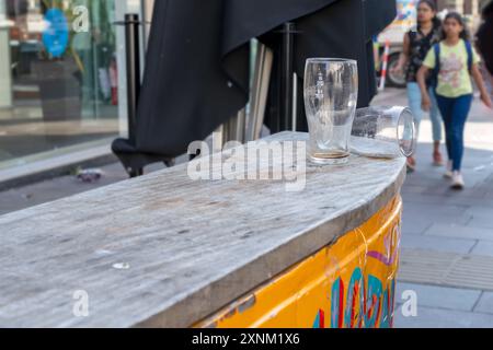 Am frühen Morgen stehen zwei leere Pint-Gläser vor einer Bar in den Straßen von Cardiff. 30/07/2024. Stockfoto