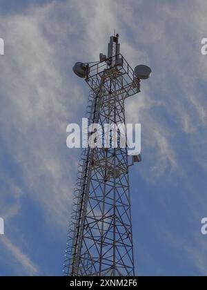 Stahlkommunikationsturm, der in den Himmel ragt, mit verschiedenen Antennen und Satellitenschüsseln. Stockfoto