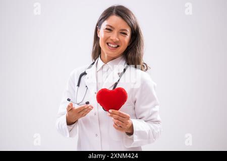 Porträt eines glücklichen Doktors, der ein herzförmiges Kissen zeigt. Stockfoto