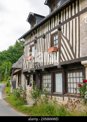 Barneville-la-Bertran, Frankreich - 25. Juli 2022: Altes Haus in Barneville la Bertran an einem bewölkten Tag im Sommer, Blumen Stockfoto