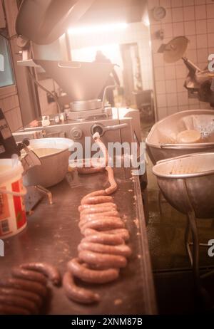 Würstchen werden in einer traditionellen Metzgerei hergestellt. Ausrüstung und Zutaten sind sichtbar und zeigen den handwerklichen Zubereitungsprozess. Stockfoto