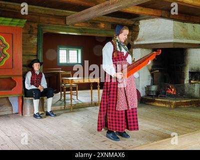 Junge Musiker in traditioneller Tracht, die für kleine Gruppen von Touristen im Volksmuseum Valdres in Fagernes in Zentral-Norwegen auftreten Stockfoto