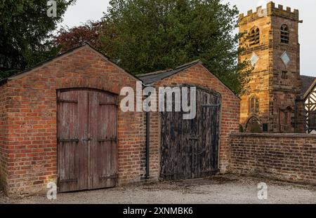 Lower Peover, Knutsford, Cheshire, Großbritannien - 30. Juli 2024 - Alte Garagen und ihre lackierten Garagentore mit abblätterndem Lack Stockfoto