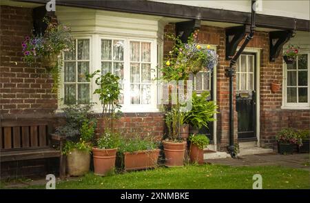 Port Sunlight, Wirral, Großbritannien - 26. Juli 2024 - zwei schwarze Türen nebeneinander in einer Reihe von Reihenhäusern mit einer Auswahl an Topfpflanzen draußen Stockfoto