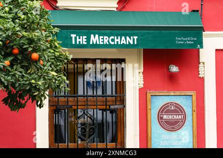 Sevilla, Spanien. 5. Februar 2024 - das Merchant Pub und Restaurant mit grüner Markise und Orangenbaum Stockfoto