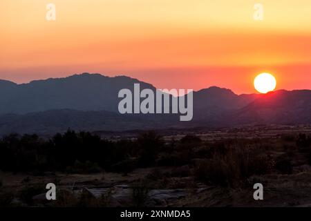 Ein herrlicher farbenfroher Sonnenaufgang über der kargen Landschaft des Augrabies Falls National Park mit den Bergen von Riemvasmaak im Hintergrund. Stockfoto