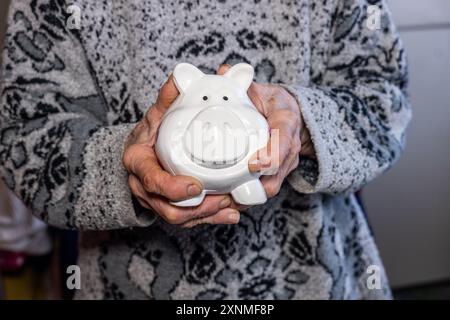 Eine alte Dame hält eine Schweinebank in den Händen. Finanzkonzept für eine Seniorin Stockfoto