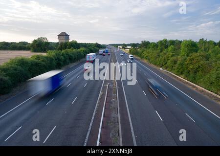 Die Autobahn M40 zwischen den Anschlussstellen 9 und 10 in der Nähe von Bicester und Oxford zeigt Autos, Lastwagen und Reisebusse, die an einem Sommerabend in Oxfordshire fahren Stockfoto