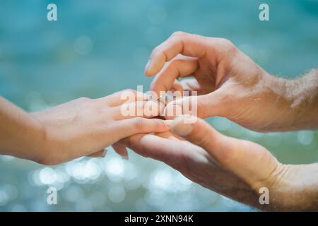 Guys Hand legt einem Mädchen einen Ehering auf die Hand Stockfoto