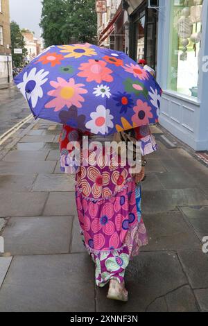 UK Weather, London, 1. August 2024: Als Gewitterstürme London überschwemmen, mit etwas willkommenem Regen nach neuem heißem Wetter, zeigt Dame Zandra Rhodes, dass Stil nicht dem Wetter geopfert werden muss. Mit einem Regenschirm mit Blumenmuster, der ihr gestuftes Kleid trocken hält, ging sie zum Abendessen zum Ivy. Quelle: Anna Watson/Alamy Live News Stockfoto