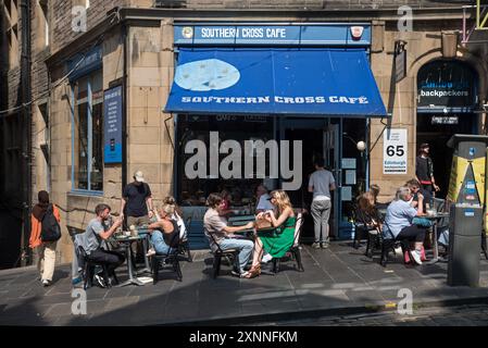 Touristen sitzen in der Sonne außerhalb des Southern Cross Cafe auf der Cockburn Street in Edinburghs Altstadt. Stockfoto