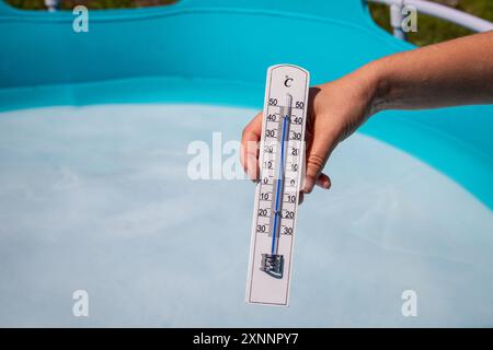 Das Thermometer zeigt 45 Grad in der Hitzewelle an, Rand des Gartenpools im Hintergrund. Stockfoto
