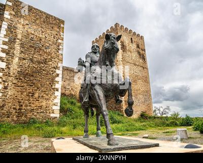 Eine Reiterstatue von Ibn Qasi, dem proklamierten politischen und spirituellen Führer des taifa-Königreichs Mertola, mit dem Turm des Schlosses Mertola Stockfoto