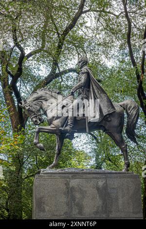New York, NY, USA - 2. August 2023: Simon Bolivar Reiterstatue am Eingang der 6th Avenue zum Central Park, Nahaufnahme mit grünem Laub und grauem Himmel als Stockfoto