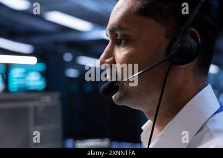 Rechenzentrumsmitarbeiter unterstützen Ingenieurteams bei der Hardwareinstallation und geben Befehle über das Headset-Mikrofon aus. Nahaufnahme eines IT-Spezialisten für Serverfarm, der mit Technikern im Ferngespräch kommuniziert Stockfoto