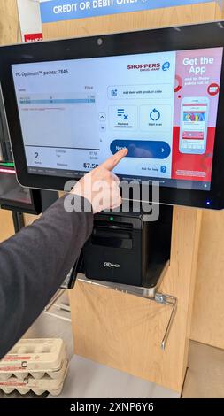 Eine Frau bezahlt mit einer Kreditkarte für ihre Artikel auf einem Touchscreen im Shoppers Drug Mart. Stockfoto