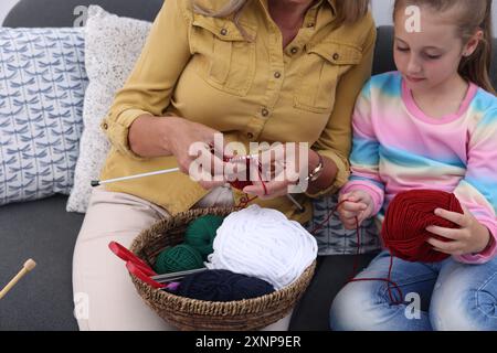 Großmutter bringt ihrer Enkelin bei, zu Hause zu stricken, Nahaufnahme Stockfoto