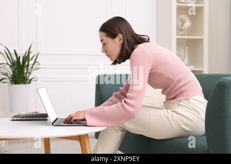 Frau mit schlechter Körperhaltung, die zu Hause einen Laptop benutzt Stockfoto